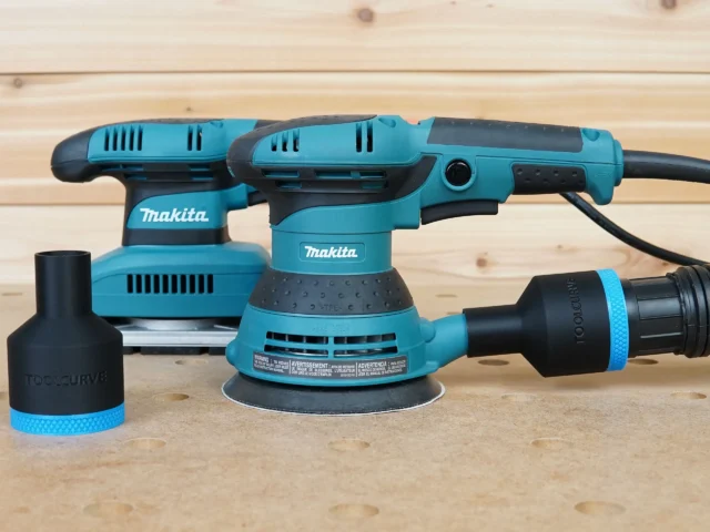 Black ToolCurve 1-7/8" hose adapter with blue band attached to a Makita 5in random orbit sander, plus a second adapter alongside
