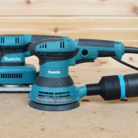 Black ToolCurve 36mm hose adapter with blue band linking a vacuum hose to a Makita 5in random orbit sander