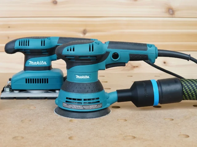 Black ToolCurve 36mm hose adapter with blue band linking a vacuum hose to a Makita 5in random orbit sander