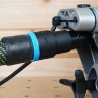 Black hose adapter with blue band attached to Dewalt miter saw dust port, connected to green and yellow braided hose