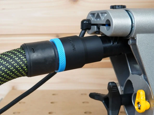 Black hose adapter with blue band attached to Dewalt miter saw dust port, connected to green and yellow braided hose