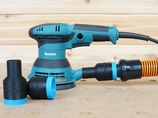 Black 1-1/4 inch ToolCurve hose adapter with blue band installed on a Makita 5in sander port, spare adapter beside it