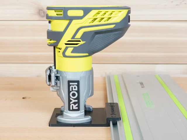 Ryobi trim router mounted on yellow and gray adapter, attached to a Kreg ACS guide rail on wooden workbench