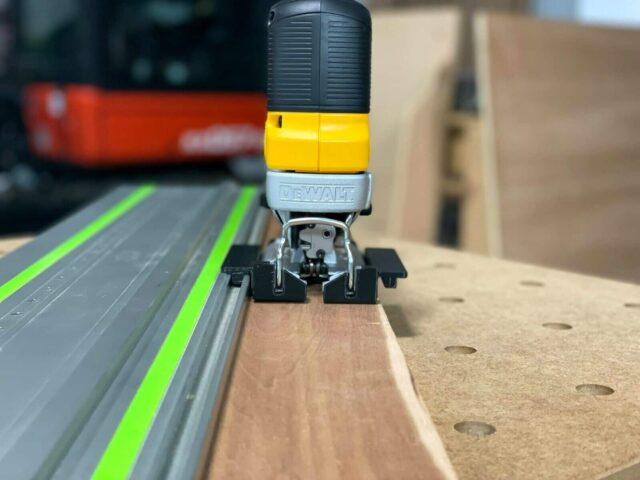 DeWalt jig saw adapter mounted on Festool track rail, showing black plastic base clamp and yellow control head attachment