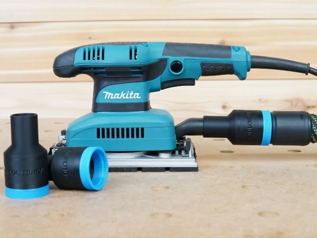 ToolCurve hose adapter for Makita sander with blue and black rubber connectors, shown alongside a Makita BO5030K orbital sander on wood