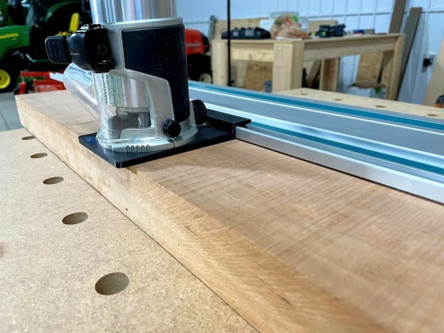 Makita trim router adapter mounted on wooden track with Festool guide rail, showing clear acrylic base and black mounting bracket