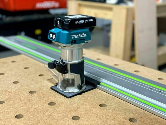 Makita trim router mounted on a clear plastic base adapter, positioned next to a bright green guide rail on a pegboard workbench