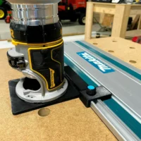 Black plastic limit stop mounted on Makita track rail with knurled knob, attached to router base on workbench