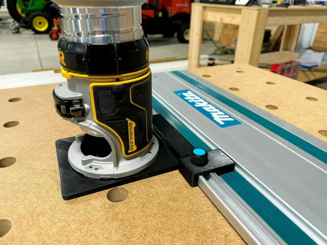 Black plastic limit stop mounted on Makita track rail with knurled knob, attached to router base on workbench