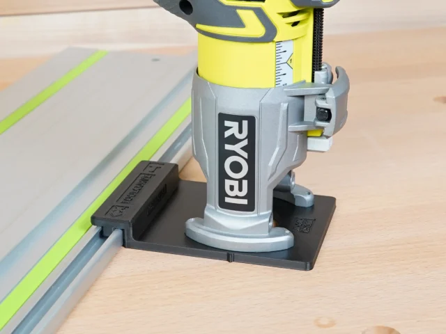 Ryobi trim router mounted on black adapter base, positioned on aluminum guide rail with yellow edge guide
