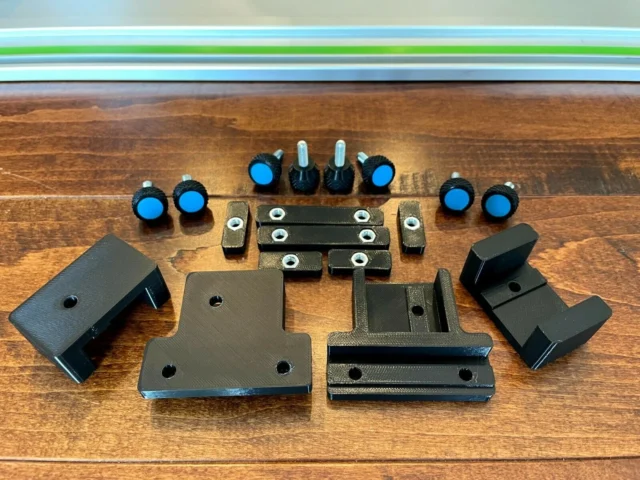 Parallel Guide system for Makita track saw displayed on wood, showing black brackets, spacers, knurled knobs with blue caps, and metal fasteners arranged flat