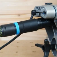 Hose adapter attached to Dewalt miter saw rear dust port, with black hose and blue band connected, mounted on gray aluminum rail