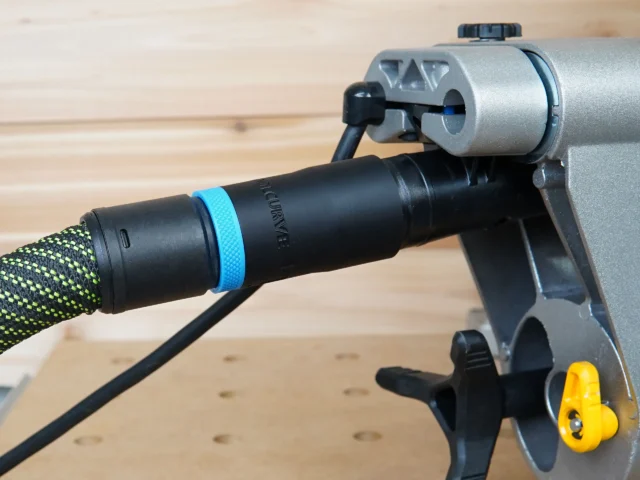 Hose adapter attached to Dewalt miter saw rear dust port, with black hose and blue band connected, mounted on gray aluminum rail
