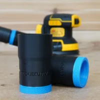Black ToolCurve hose adapter with blue grip band, shown in foreground with a DeWalt sander blurred in the background