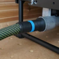 Black hose adapter with blue band attached to green-and-black Festool hose, mounted on Dewalt table saw dust port