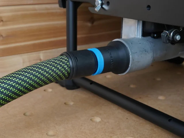 Black hose adapter with blue band attached to green-and-black Festool hose, mounted on Dewalt table saw dust port