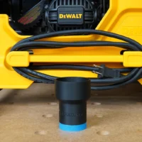 Black ToolCurve hose adapter with blue grip band, positioned at the front dust port of a yellow DeWalt table saw