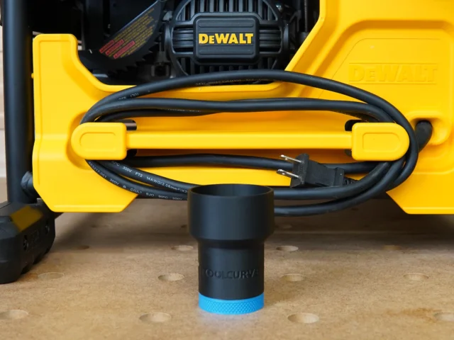 Black ToolCurve hose adapter with blue grip band, positioned at the front dust port of a yellow DeWalt table saw