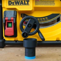 Black ToolCurve hose adapter with blue band seated in front of a yellow Dewalt table saw, showing the threaded connection point
