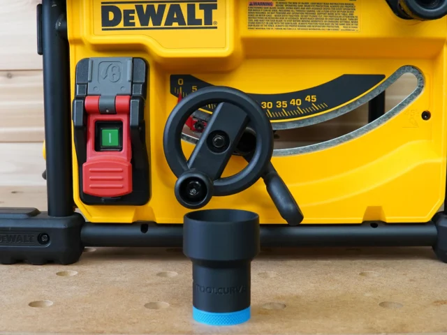 Black ToolCurve hose adapter with blue band seated in front of a yellow Dewalt table saw, showing the threaded connection point