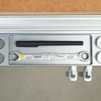 Aluminum utility rack mounted on workbench profile with two bench dogs, pen holder, and Wera wrench displayed inside