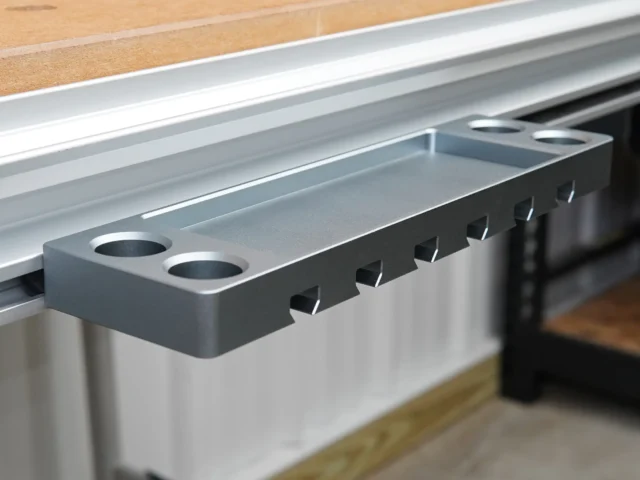 Gray aluminum utility rack with six slots for clamps and two holes for bench dogs, mounted on a Festool MFT workbench t-track
