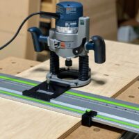 Bosch 1617 plunge router mounted on LR 32 rail adapter with black mounting plate, positioned over Festool track saw rail on wooden workbench
