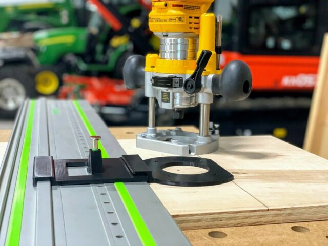 Dewalt plunge router mounted on aluminum track rail with black ToolCurve LR32 adapter plate and spring-loaded knob positioned on wooden workpiece