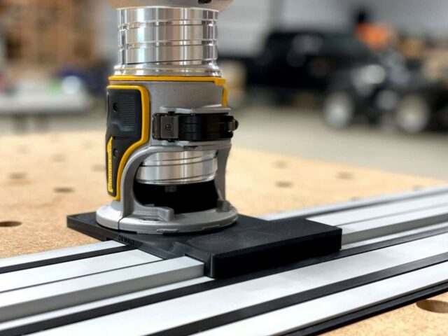 Dewalt router adapter mounted on Dewalt guide rail track, showing black base plate attached to aluminum rail