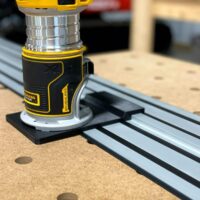 Dewalt trim router mounted on black adapter base attached to Dewalt aluminum guide rail track