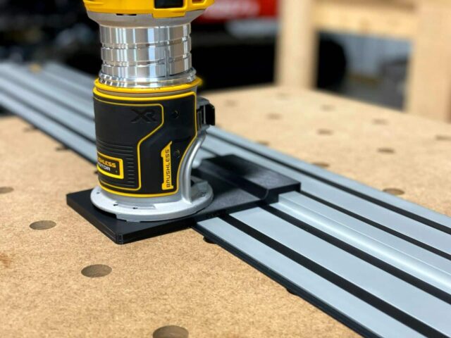 Dewalt trim router mounted on black adapter base attached to Dewalt aluminum guide rail track