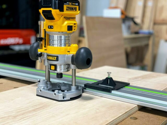 DeWalt trim plunge router mounted on aluminum guide rail with ToolCurve LR32 plate and spring-loaded knob attached to base