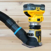 Hose adapter cover attached to a DeWalt trim router with dust collection hose connected, showing the adapter mounted to the router base
