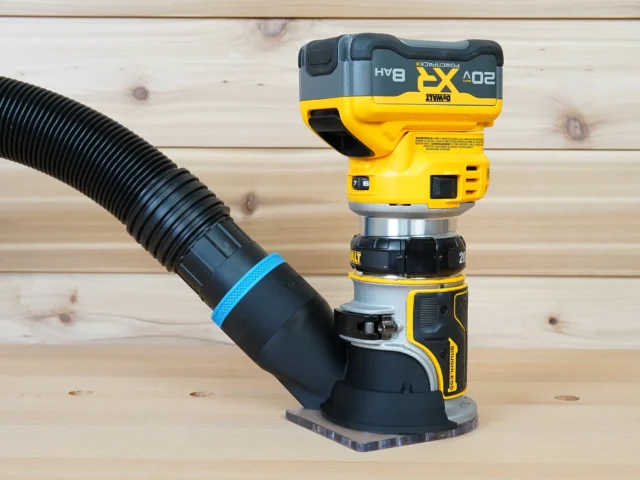 Hose adapter cover attached to a DeWalt trim router with dust collection hose connected, showing the adapter mounted to the router base