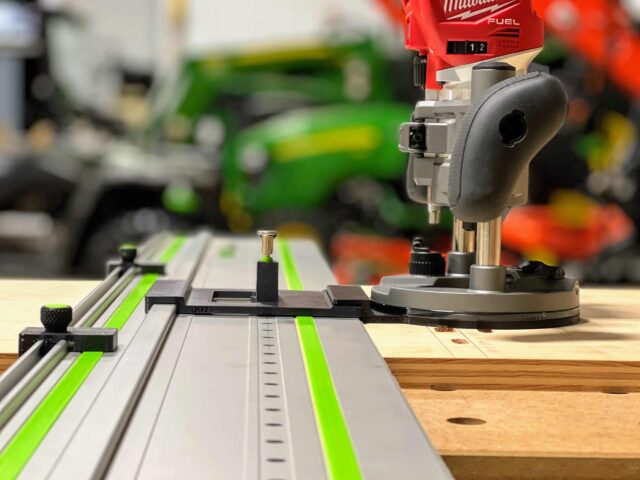 Milwaukee trim plunge router mounted on FS rail system with ToolCurve LR32 adapter plate and spring-loaded positioning knob engaged on wooden workpiece
