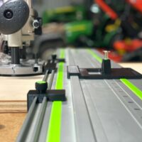 Makita plunge router mounted on Festool FS rails with ToolCurve LR32 adapter plate and guide stops, showing drilling setup from above