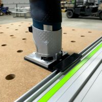 Bosch Colt router mounted on gray and black plastic adapter, seated on a Festool FS guide rail with bright green center strip