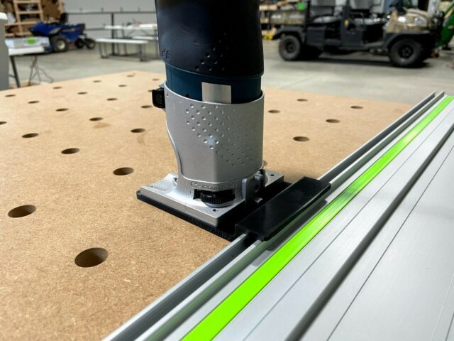 Bosch Colt router mounted on gray and black plastic adapter, seated on a Festool FS guide rail with bright green center strip