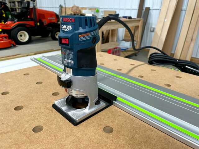 Bosch Colt 1HP router mounted on an aluminum guide rail with bright green stripe, white base adapter connecting router to rail