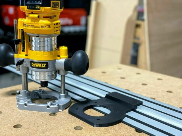 Dewalt plunge router attached to Dewalt track saw track, showing black adapter base mounted on aluminum rail with guide holes