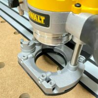 Dewalt plunge router mounted on adapter attached to Dewalt track saw rail, showing threaded mounting points and curved base