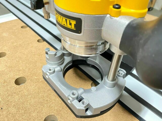 Dewalt plunge router mounted on adapter attached to Dewalt track saw rail, showing threaded mounting points and curved base