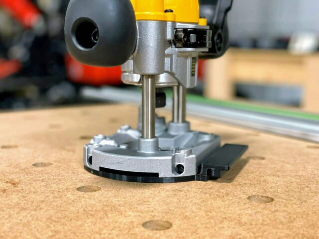 Dewalt plunge router DNP612 base with ToolCurve guide rail adapter mounted on wood workbench near reference holes