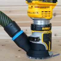 Black hose adapter with blue band attached to DeWalt trim router base, connected to green-and-black hose