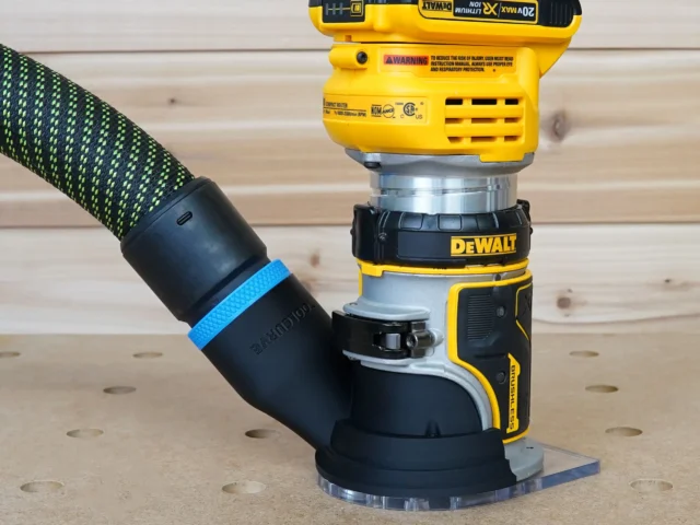 Black hose adapter with blue band attached to DeWalt trim router base, connected to green-and-black hose