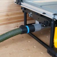 Black 36mm hose adapter with blue ring joining a green vacuum hose to a Dewalt table saw's rear dust port