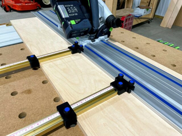 Black plastic parallel guide clamps mounted on Kreg ACS rail system with track saw positioned above wooden workpiece