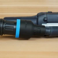 Black plastic hose adapter with blue band, attached to Festool sanding tool with ribbed hose connection on left side