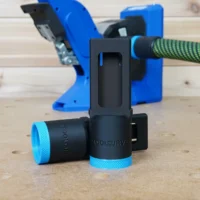 Black and blue hose adapter with 27mm Festool hose attached, shown in front of a Kreg 720 pocket-hole jig on a workbench