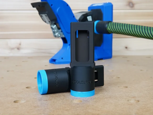Black and blue hose adapter with 27mm Festool hose attached, shown in front of a Kreg 720 pocket-hole jig on a workbench